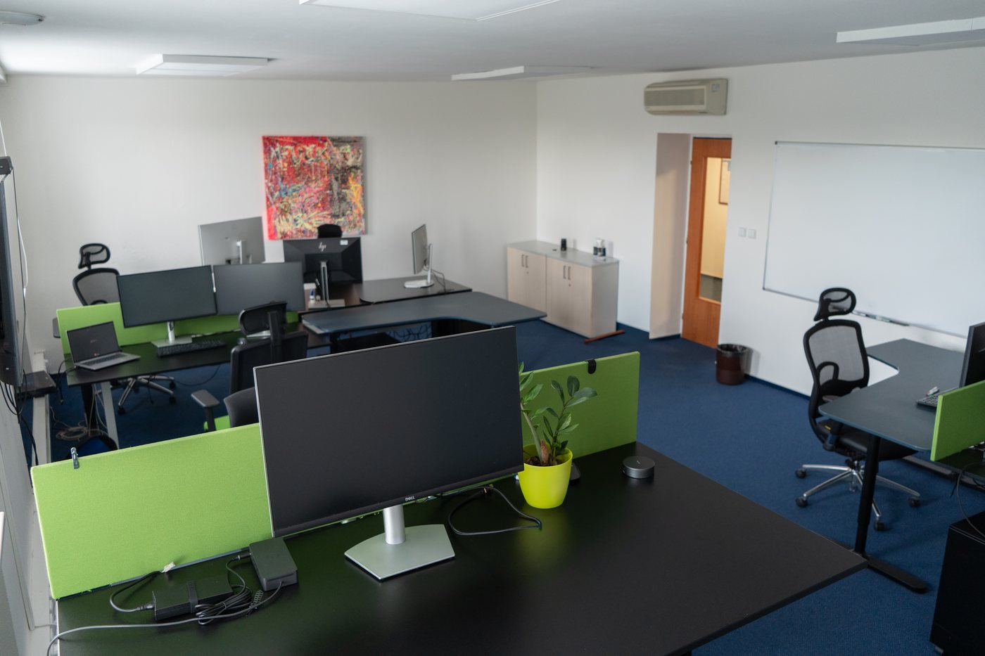 Pracovní místa v coworku - stoly s paravány a monitory